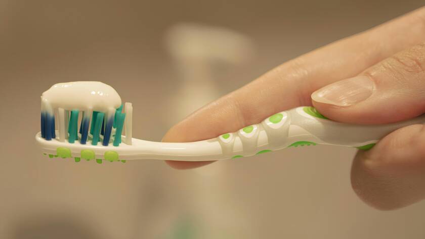 a person is holding a toothbrush with toothpaste on it